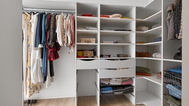 Walk-in closet innredet med åpne garderobeløsninger, skuffer og hyller.