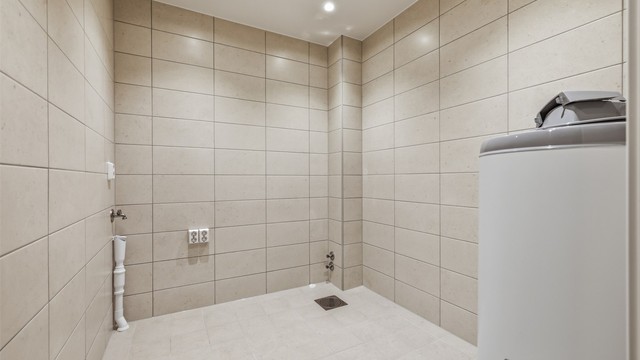 Separat vaskerom med fliser, gulvvarme og opplegg for vaskemaskin.
