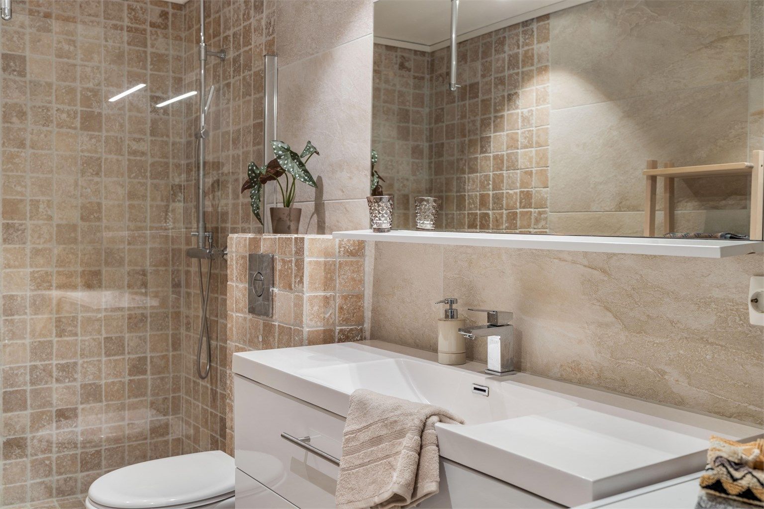 Innredning med nedfelt servant og veggmontert toalett.