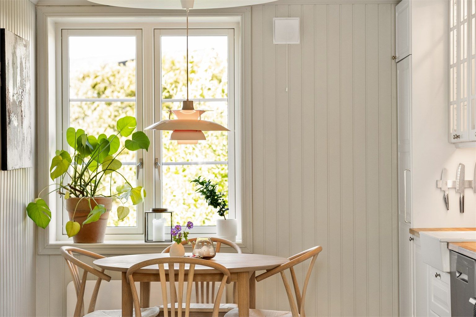 Lysmalte panelplater på vegger og to-fløyede sprossevinduer setter rammene for en klassisk atmosfære.
