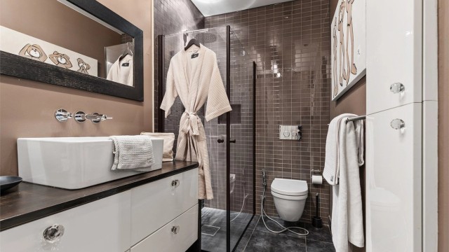 Vegghengt servantinnredning med skuffer. Ovenpåliggende servant med ett-greps armatur. Speil over servant.