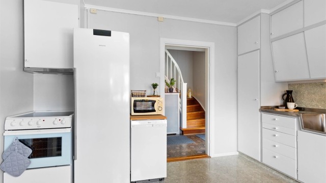 Plass for komfyr med platetopp, frittstående kjøleskap og oppvaskmaskin. og ventilator i overskap.