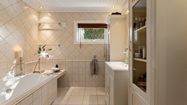 Flislagt baderom i underetasjen med innfliset badekar og downlights i taket.