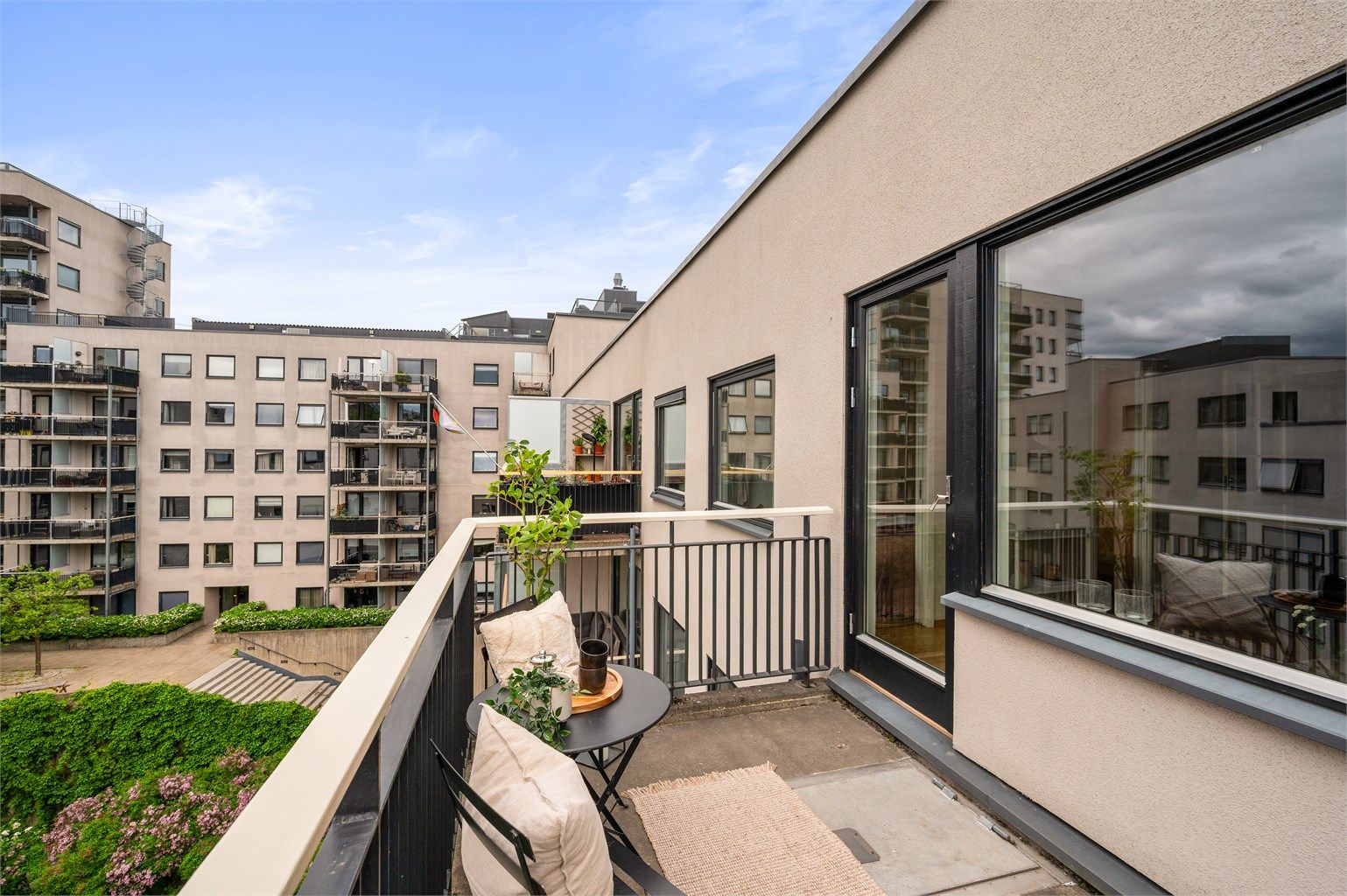 Balkongen vender mot en rolig bakgård, og fungerer som en naturlig forlengelse av stuen på varme sommerdager.