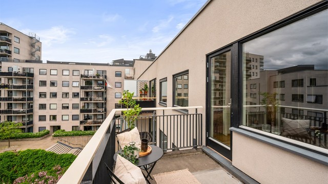 Balkongen vender mot en rolig bakgård, og fungerer som en naturlig forlengelse av stuen på varme sommerdager.