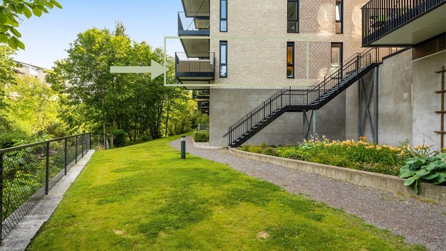 Eiendommen grenser til grøntområder med tursti langs elven. Selv om leiligheten ligger i 1. etasje fremstår den nærmest som en 2. etasje sett fra balkongsiden.