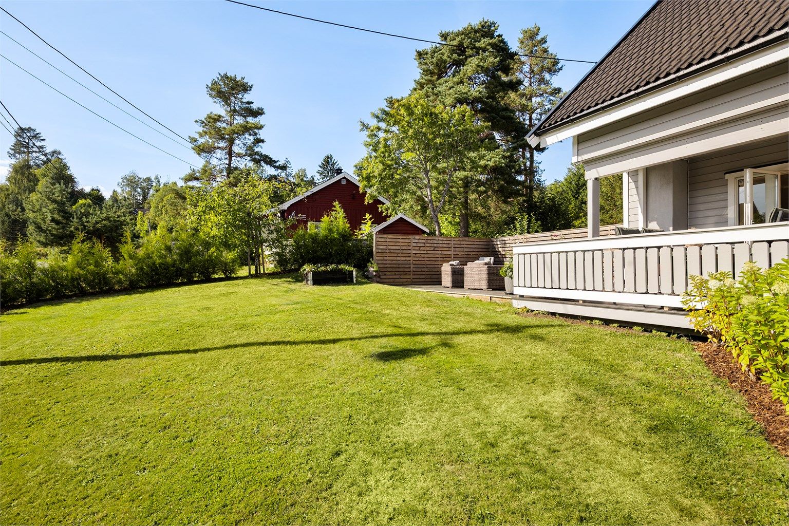 Tomten er pent opparbeidet med gressplen, hekk, barkedbed og diverse beplantninger.