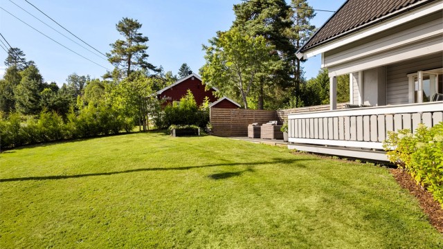 Tomten er pent opparbeidet med gressplen, hekk, barkedbed og diverse beplantninger.
