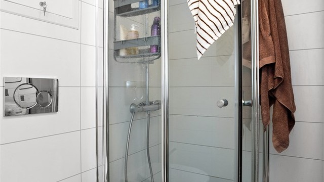 Dusjhjørne med glassdører og vegghengt toalett.