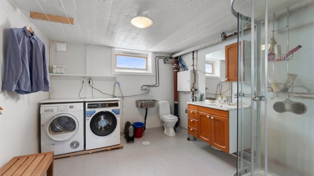 Praktisk kombinert bad og vaskerom med dusjkabinett og opplegg for vaskemaskin.