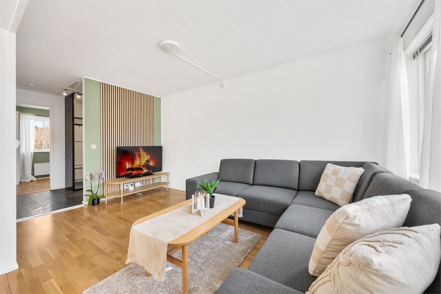 Den innbydende stuen har store vindusflater som slipper inn rikelig med naturlig lys og skaper en luftig og behagelig atmosfære