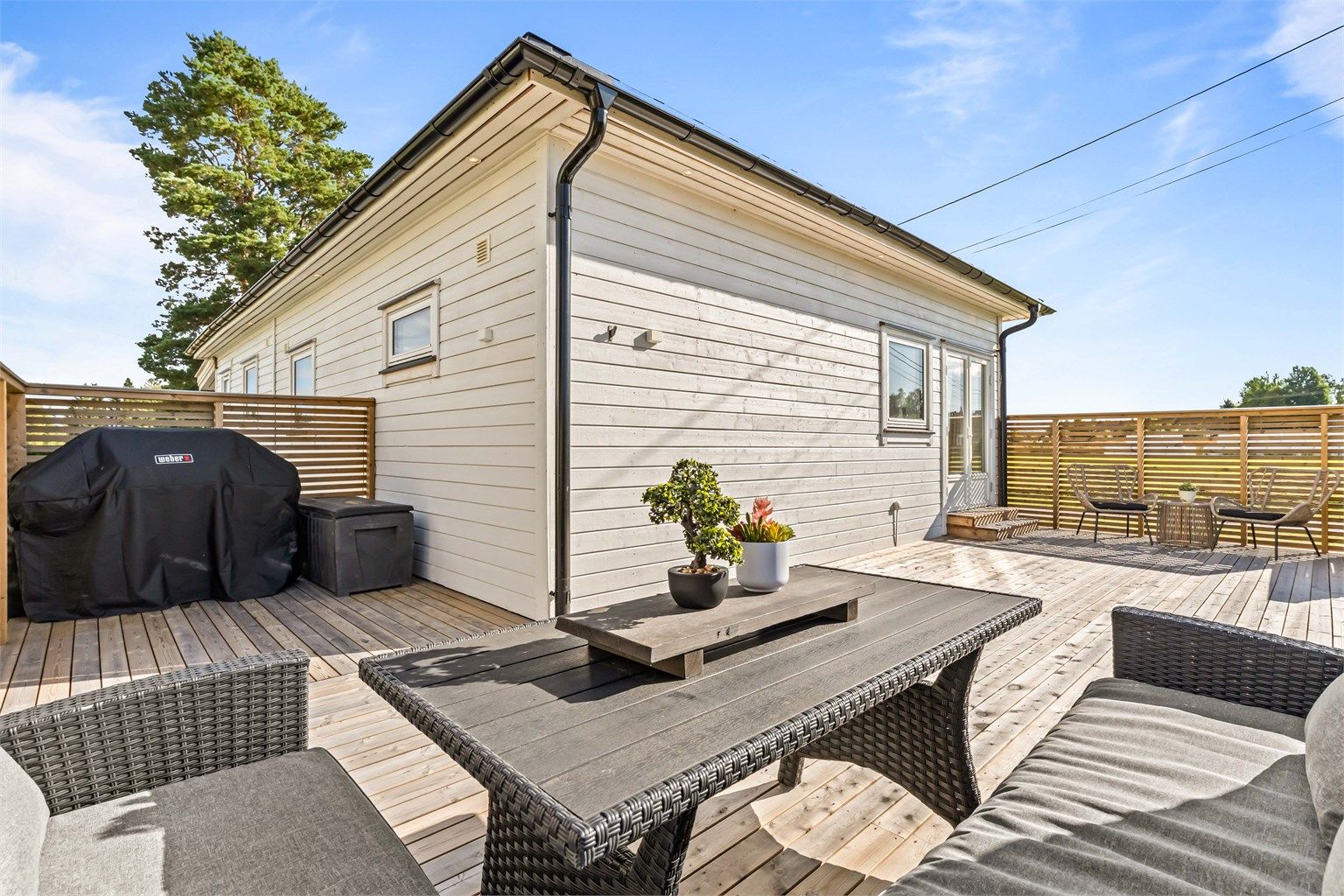 Romslig terrasse med rikelig plass til grill og flere sittegrupper.