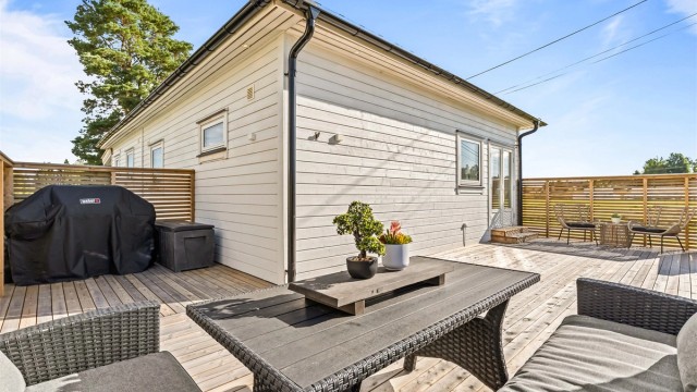 Romslig terrasse med rikelig plass til grill og flere sittegrupper.