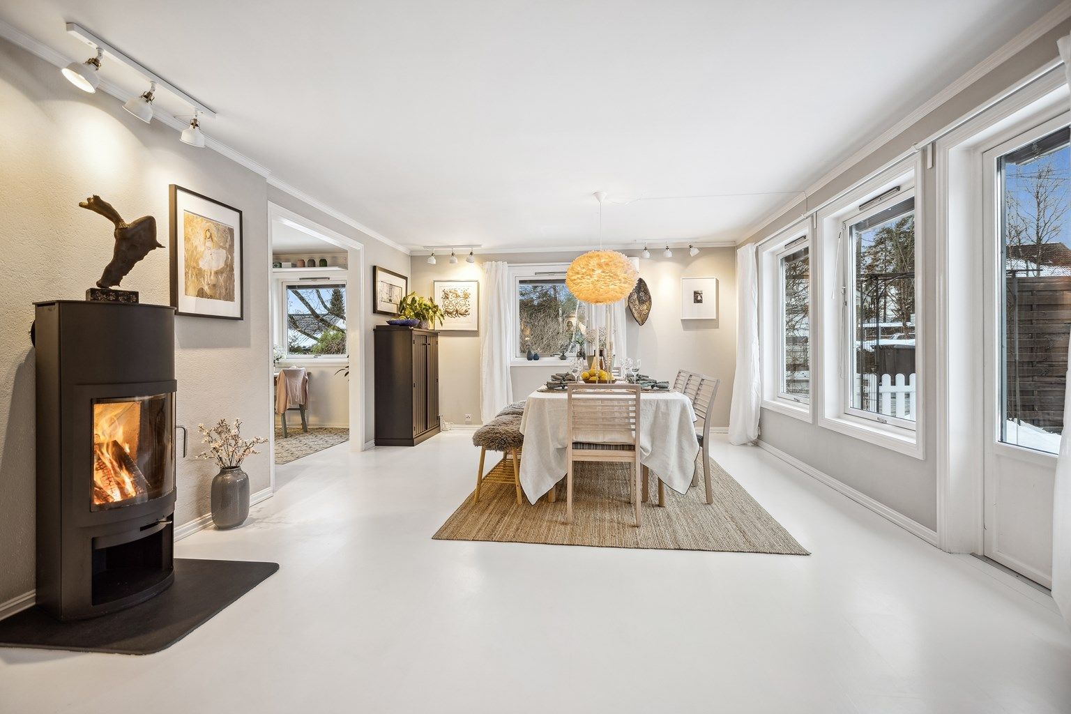 Lys og delikate stue og spisestue  i åpen løsning. Naturlig lys strømmer inn gjennom store vinduer og skaper en innbydende atmosfære.