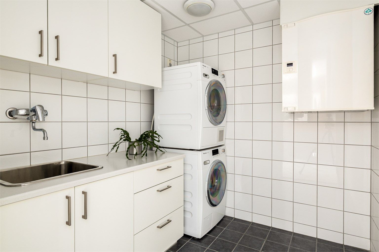 Eget praktisk vaskerom. Her er det godt med skapplass og opplegg for både vaskemaskin og tørketrommel.