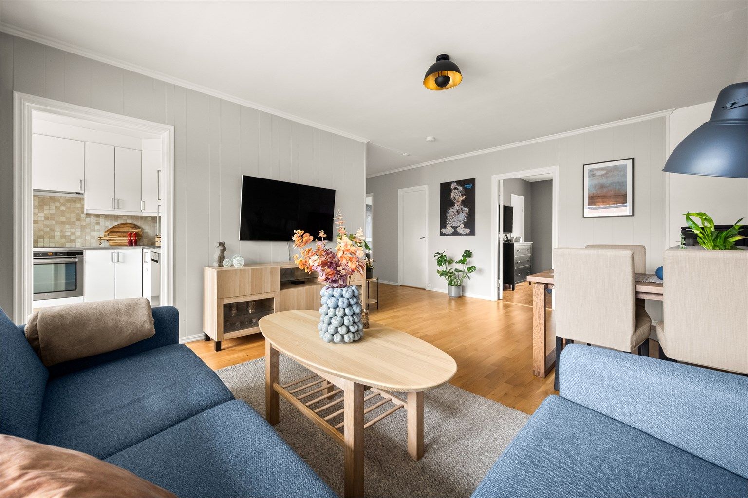 Gjennomgående parkettgulv binder rommene sammen og skaper en helhetlig og varm atmosfære i leiligheten.