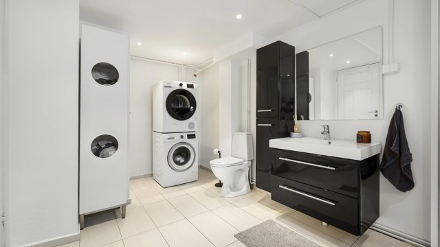 Bad i kjelleren kombinert med vaskerom. Varmekabler i gulvet og downlights. Varmtvannsbereder står i eget kott i hjørnet.