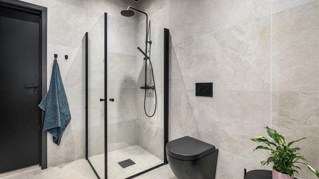 Gjestebadet er fullt utstyrt, som hovedbadet med mange kontrasterende sorte elementer. Flisene er her i en varm nyanse.