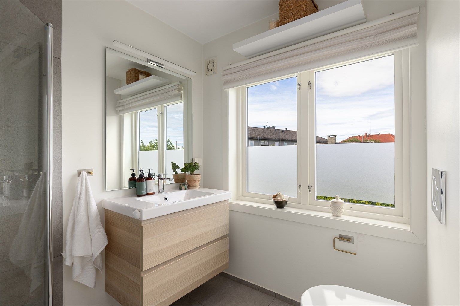 Lekkert "en suite" bad som ble oppusset i 2017. Dusjhjørne med innfellbare dusjvegger i glass. Grå fliser på vegg og mosaikkfliser på gulv i dusjsone. Vegghengt toalett og servantskap med speil og overlys.