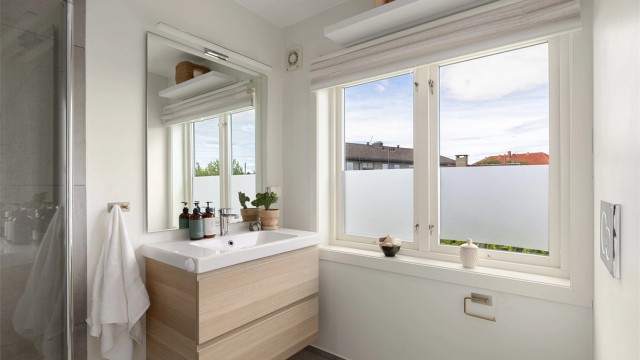 Lekkert "en suite" bad som ble oppusset i 2017. Dusjhjørne med innfellbare dusjvegger i glass. Grå fliser på vegg og mosaikkfliser på gulv i dusjsone. Vegghengt toalett og servantskap med speil og overlys.