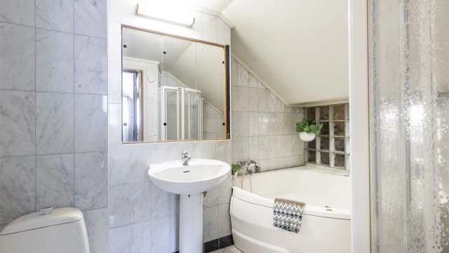 Badet inneholder dusjnisje, badekar, servant og toalett