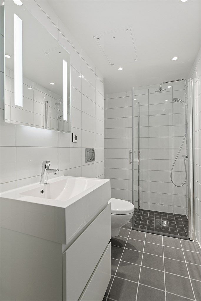 Badet fremstår som meget flott og stilrent, med grå fliser på gulvet og store, hvite fliser på veggene. Gulvvarme gir ekstra komfort og rommet er utstyrt med opplegg for vaskemaskin.