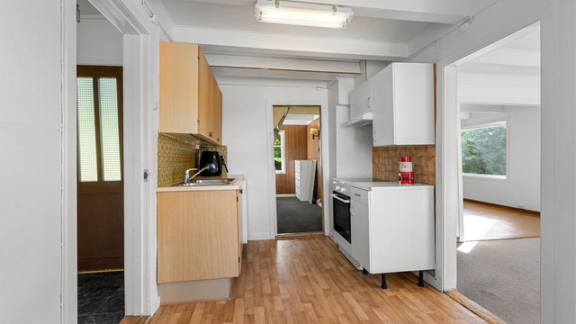 Kjøkkenet har innredning med finerfronter og benkeplate med laminert overflate.