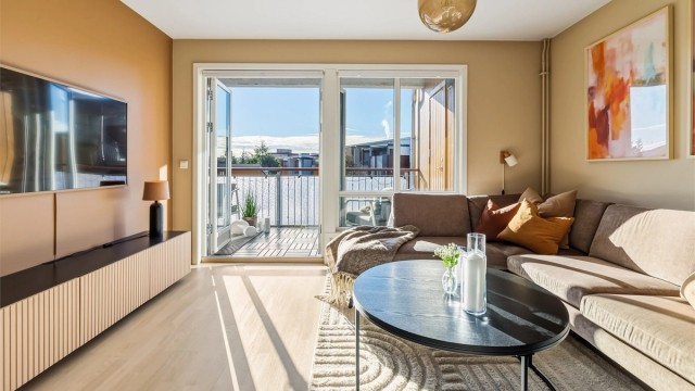 Romslig stue med store vindusflater som sikrer leiligheten rikelig med naturlig lys.