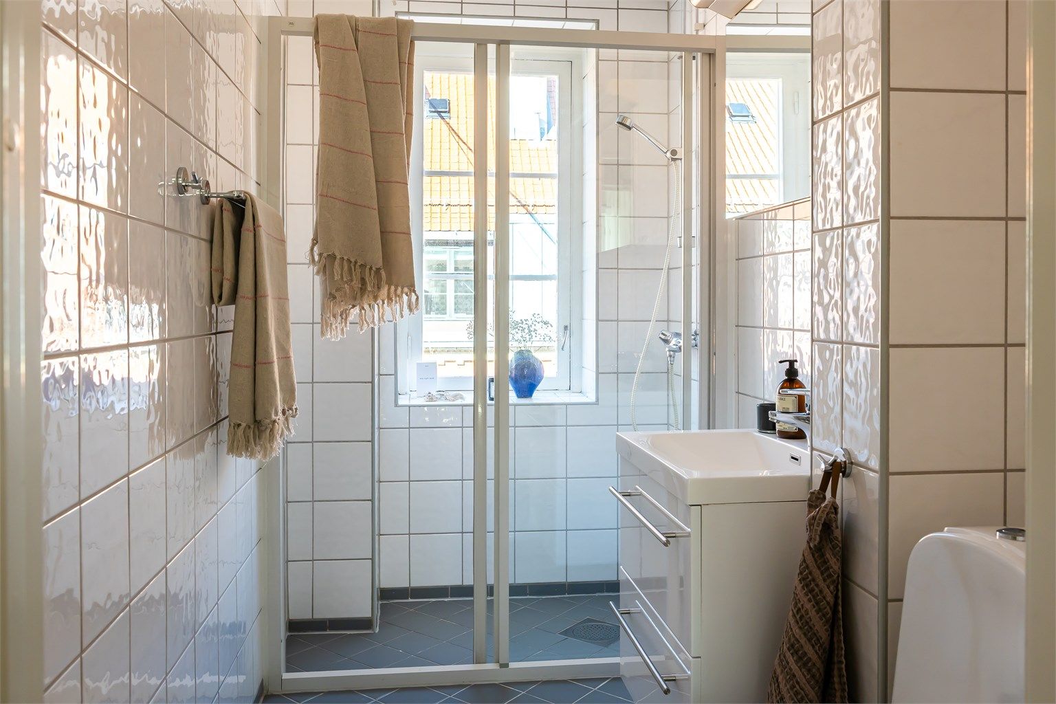 Baderommet har lyse og tidløse fliser på både vegger og gulv (elektrisk varme i gulv). Vindu gir naturlig dagslys og bidrar til en åpen og frisk atmosfære.



