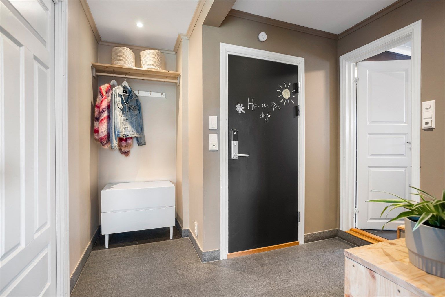 Man kommer inn i en lys og innbydende entré, der inngangsdøren er utstyrt med elektronisk kodelås.