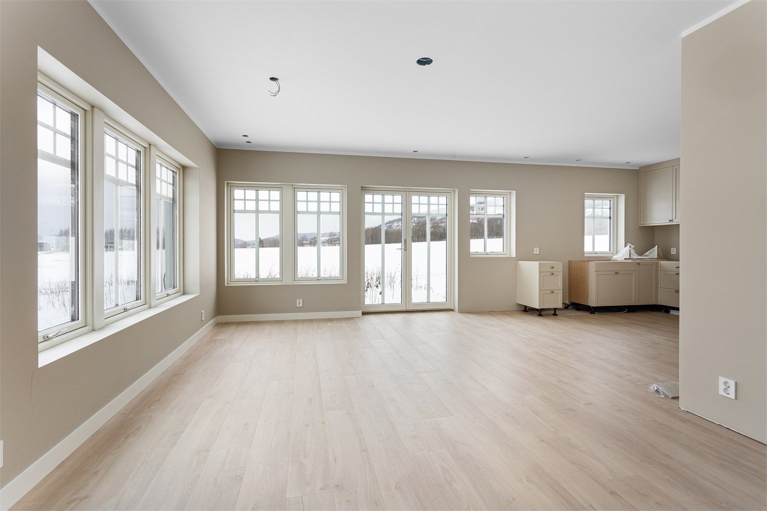 Første etasje har en åpen løsning mellom stue og kjøkken, med store vindusflater.