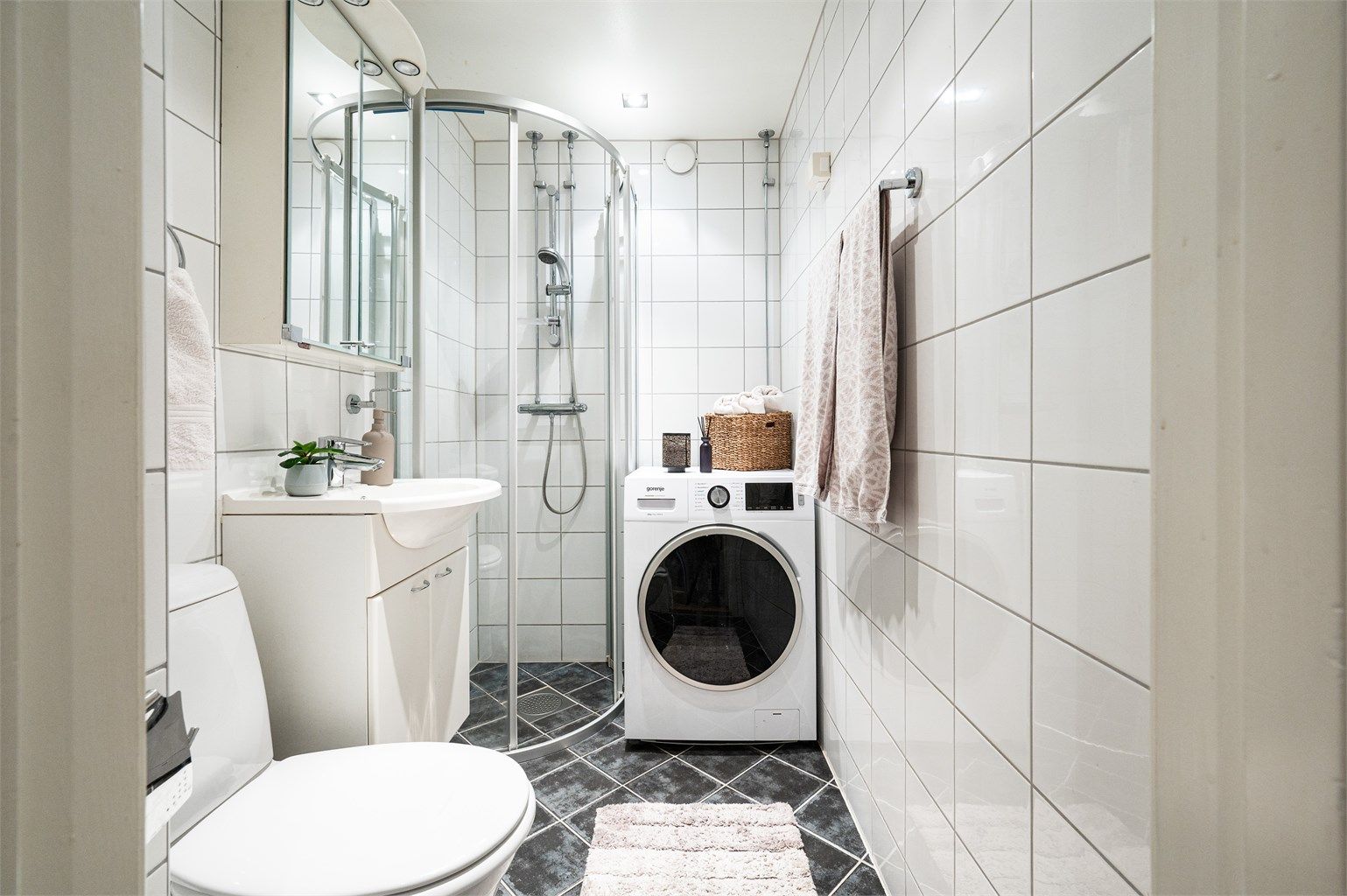 Badet er utstyrt med dusjhjørne, servantinnredning og har opplegg for vaskemaskin.