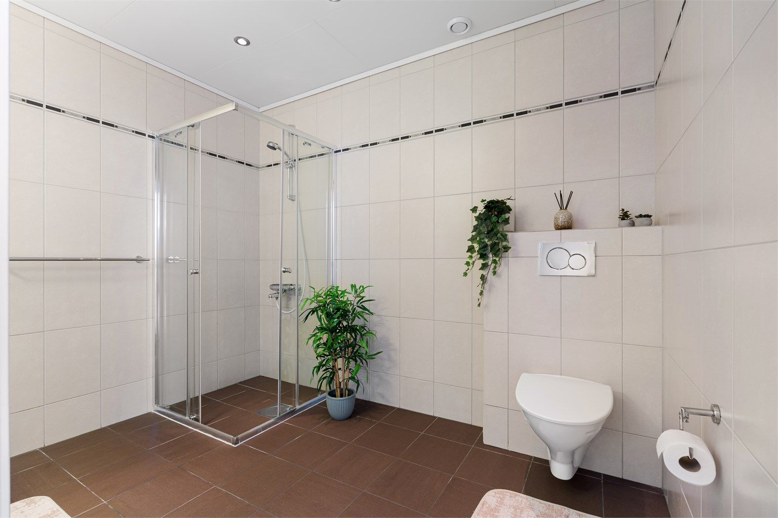 Videre er badet innredet med dusjhjørne og vegghengt toalett.