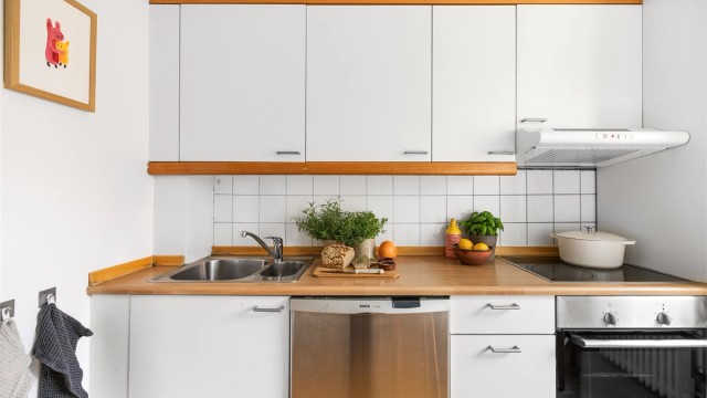 Kjøkkeninnredningen har slette fronter, laminatbenkeplate og fliser over benken som gir et lyst og tidløst uttrykk.