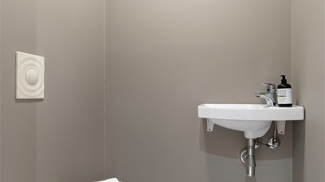 Leiligheten har et praktisk, separat toalettrom med vegghengt toalett og servant.