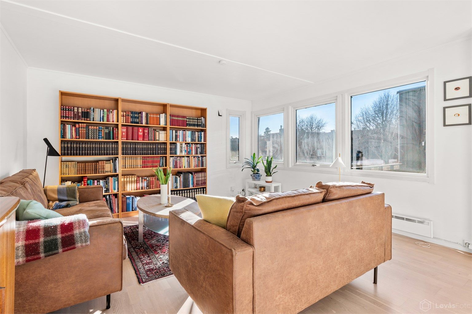 En lys og trivelig stue med gjennomgående parkettgulv.