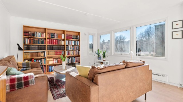 En lys og trivelig stue med gjennomgående parkettgulv.