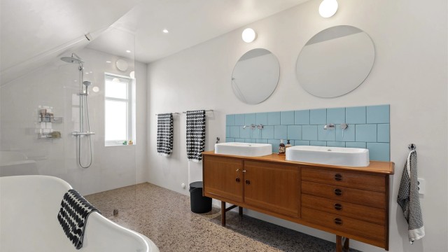 Et romslig og lekkert bad med både dusjnisje og et frittstående badekar av støpejern. Det er gulvvarme og innfelte downlights i taket.