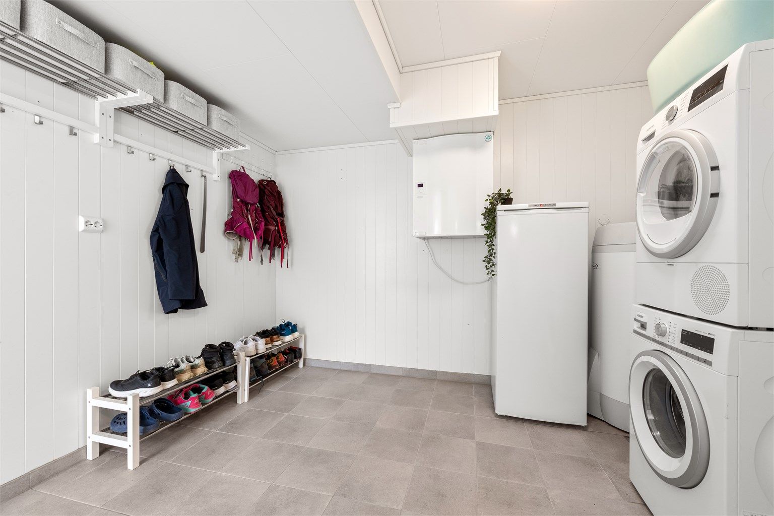 Romslig og praktisk vaskerom med flislagt gulv. Her er det opplegg for vaskemaskin, og boligens varmtvannsbereder på 200 liter fra 2017 er plassert her.