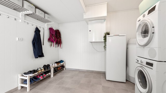Romslig og praktisk vaskerom med flislagt gulv. Her er det opplegg for vaskemaskin, og boligens varmtvannsbereder på 200 liter fra 2017 er plassert her.