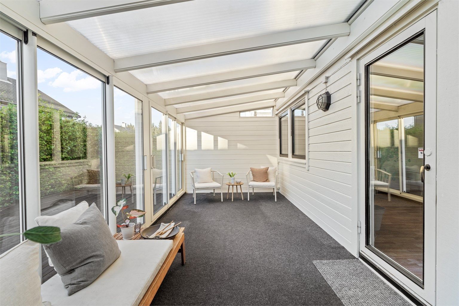 Innglasset hagestue innredet som et ekstra oppholdsrom skjermet for vær og vind.