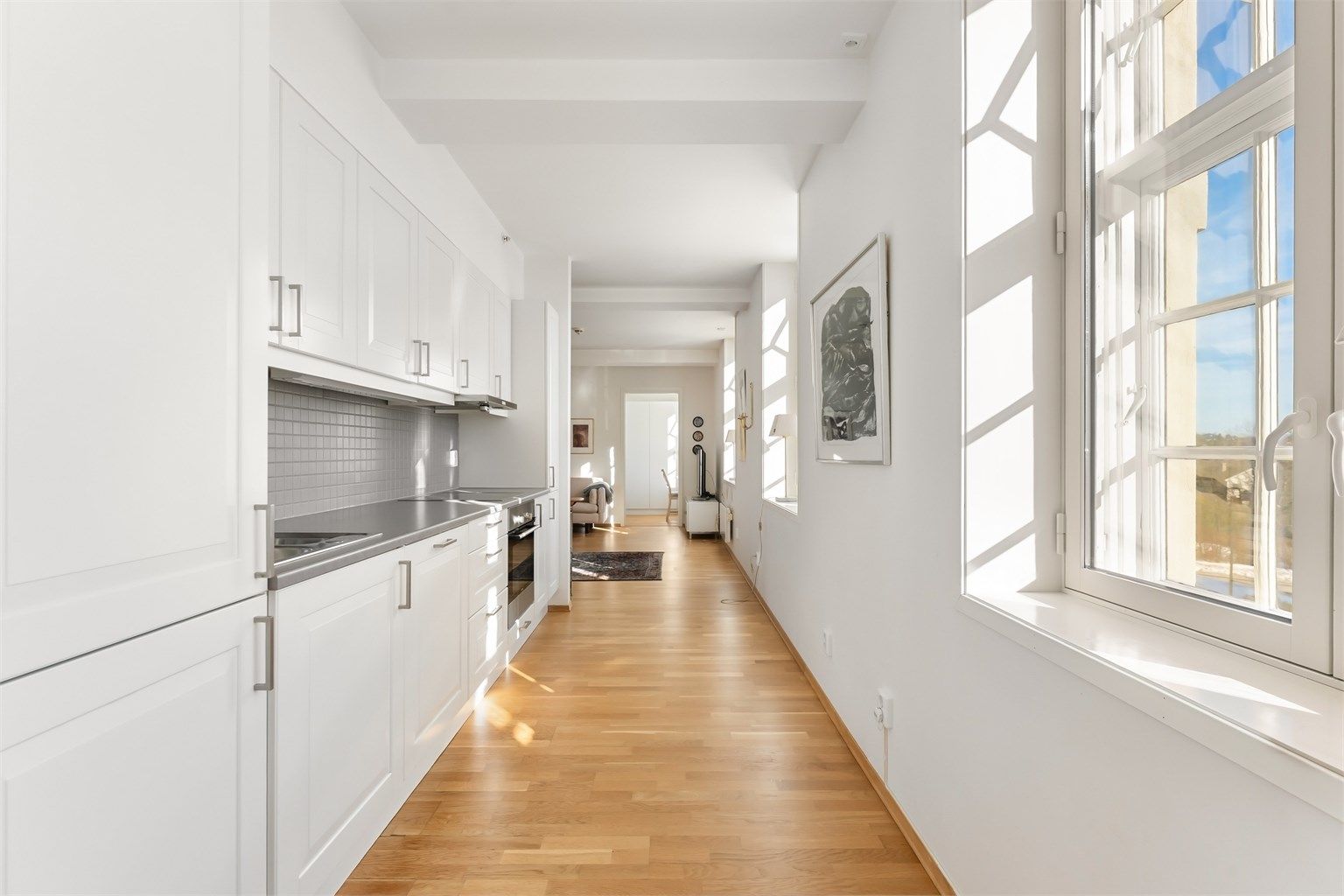 Fliser over kjøkkenbenken og belysning under overskapene er praktiske detaljer.