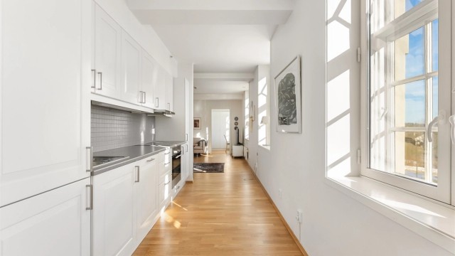 Fliser over kjøkkenbenken og belysning under overskapene er praktiske detaljer.