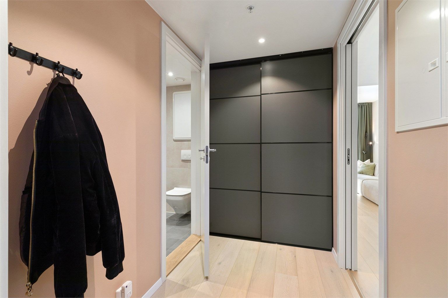 Romslig entré/gang med skyvedørsgarderobe og veggplass for klesoppheng