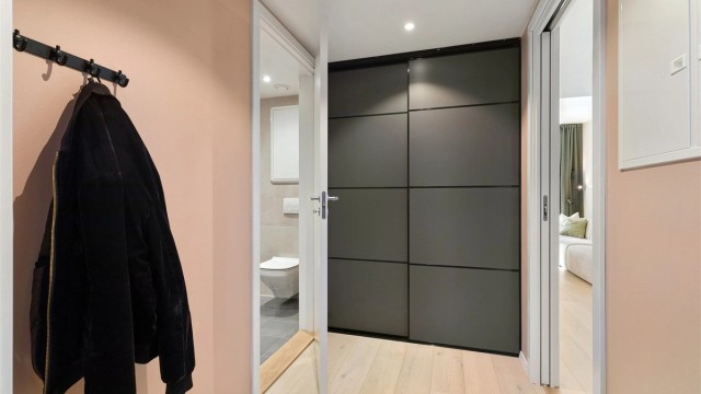 Romslig entré/gang med skyvedørsgarderobe og veggplass for klesoppheng