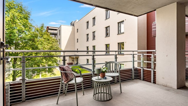 Den romslige svalgangen gir plass til en liten sittegruppe. Leiligheten ligger ytterst, og har ikke gangtrafikk forbi.