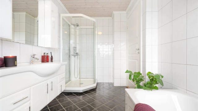 Badet er utstyrt med dusjkabinett med dusjarmatur, badekar med vegghengt badekararmatur og gulvstående toalett.