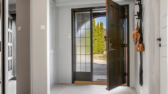 En romslig entré ønsker deg velkommen inn. Her er det flislagt gulv og skyvedørsgarderobe.