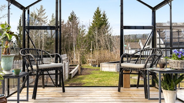 Fra drivhuset ser man ut over hagen med plenarealer og plantekasser.