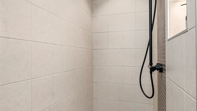 Badet har en romslig dusjsone med både takdusj og hånddusj. Badet er videre innredet med badekar, vegghengt toalett og praktiske oppbevaringsløsninger i en gjennomført utførelse.